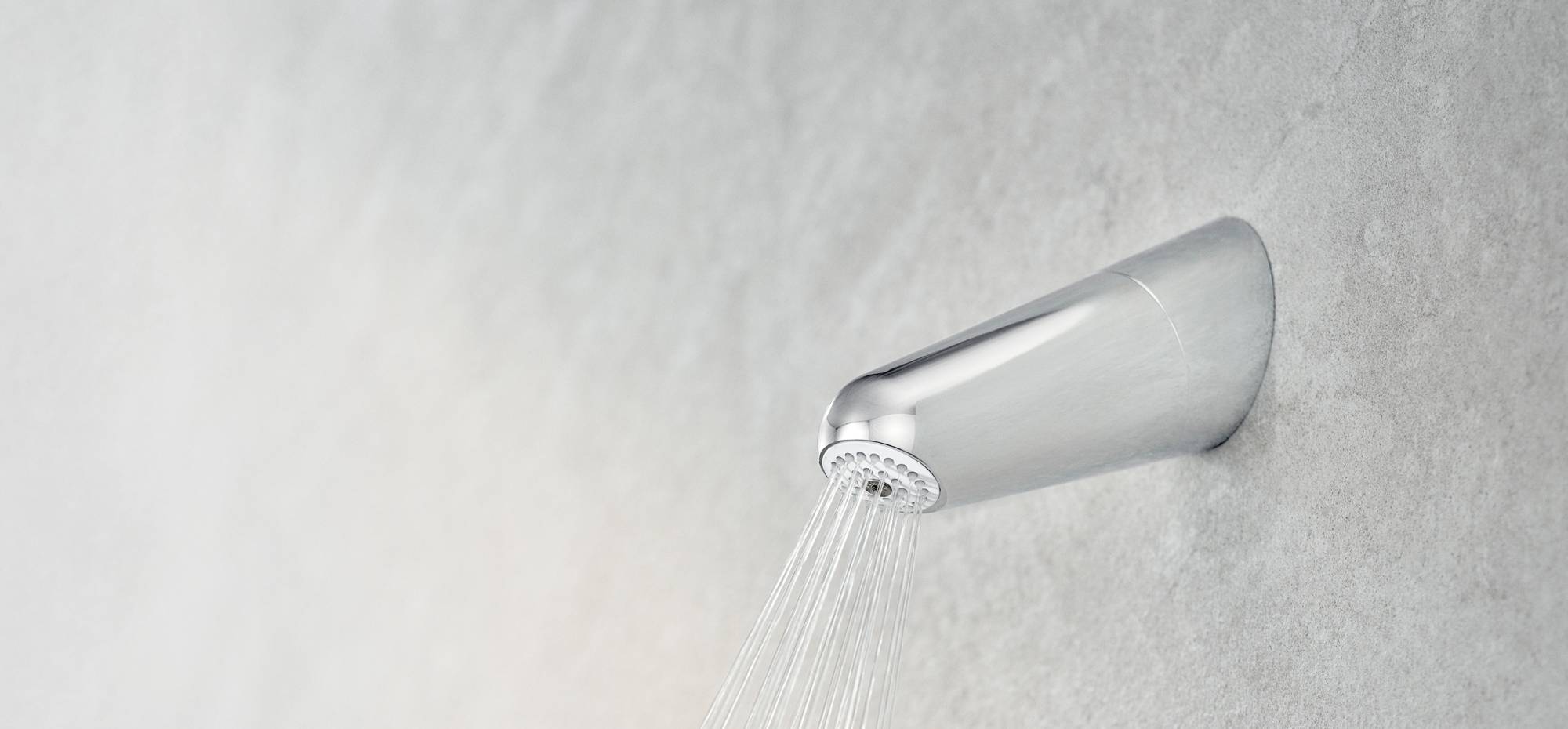Side view of the Chrome Wall Shower Filter on a grey wall, with water flowing from the nozzle.