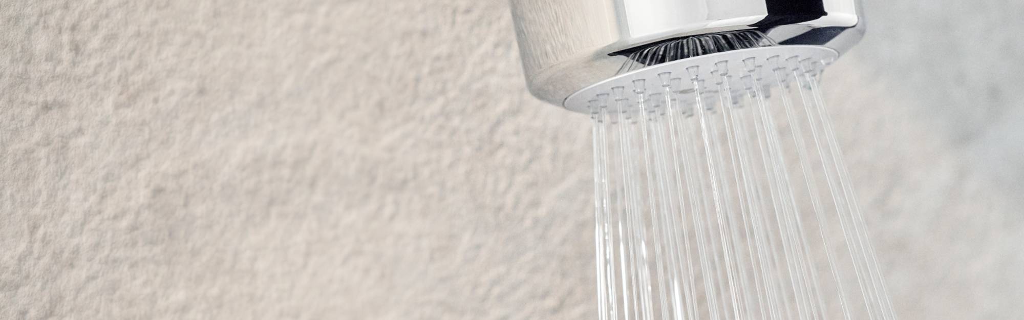 Close up of Easy-Fix Shower Filter mounted to the wall, with a steady stream of water.