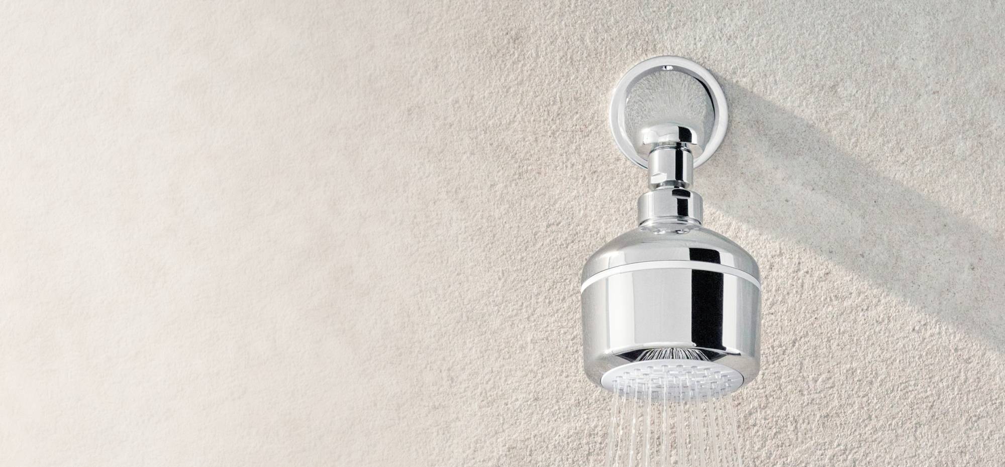 Angled view of Easy-Fix Shower Filter mounted to the wall, with a steady stream of water.